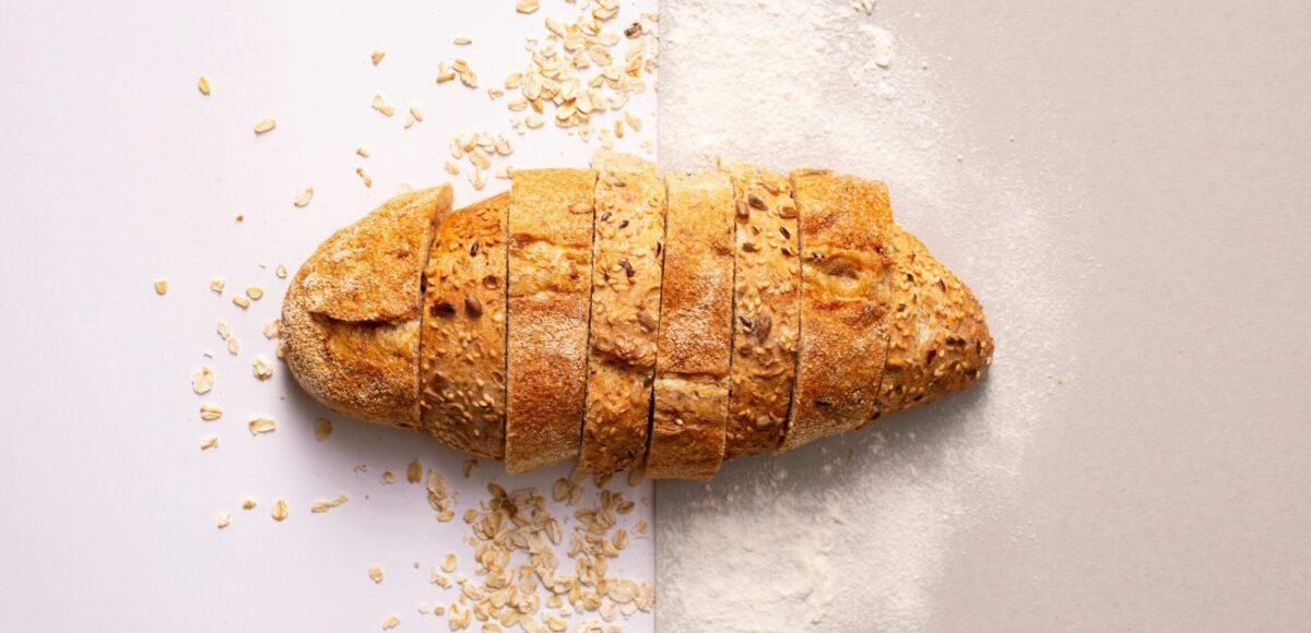 Freshly sliced whole grain bread with oats and flour provides a rustic and nutritious appeal.