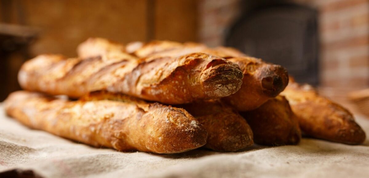 Warm, freshly baked rustic baguettes stacked in a cozy bakery setting.